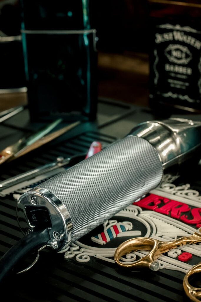 Close-up of barber tools including electric razor and scissors on a salon counter.